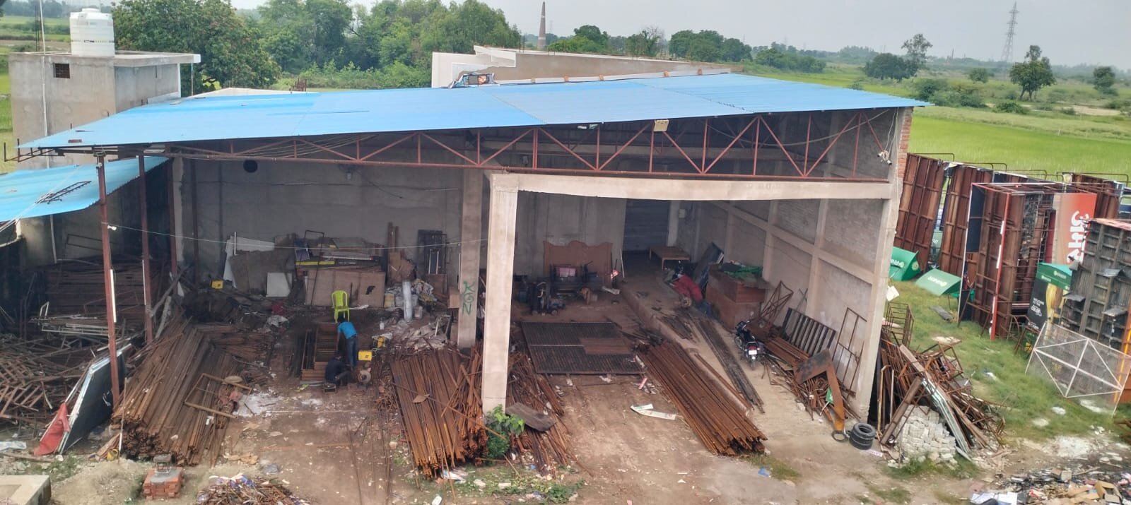 Aerial view of Rudra's in-house fabrication yard with steel stock and workshop shed